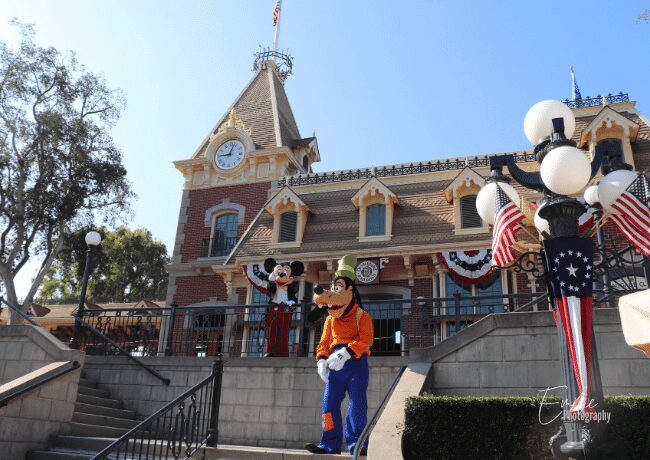 Mickey Mouse, the beloved Disney character, standing in the heart of Disneyland, surrounded by enchanting attractions and cheerful visitors.