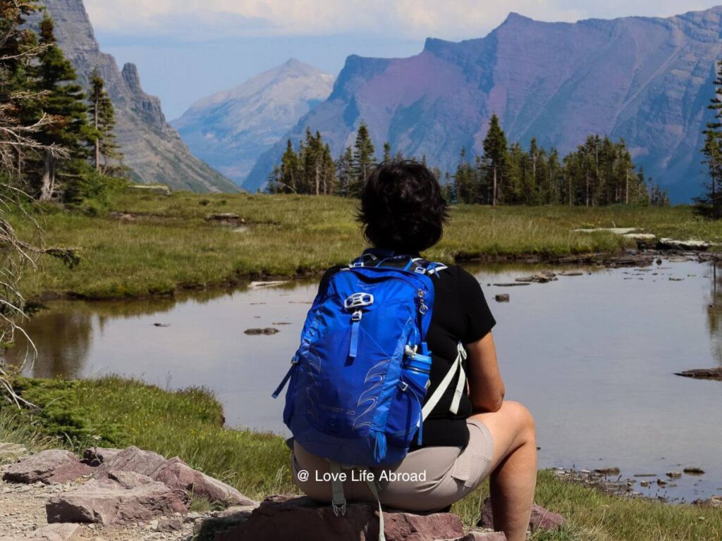 A woman sitting on a rock by a lake in Glacier National Park